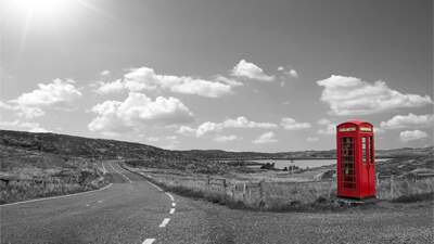 red telephone box beside an empty road